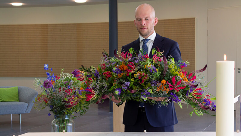 Jerry met een bloemstuk bij de kist